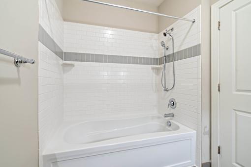 A white bathroom with a white tub and a white shower. at Pennsauken Golf Course Villas, PENNSAUKEN