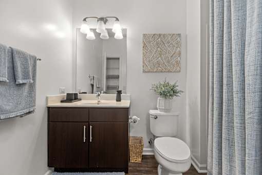 A bathroom with a toilet, sink, and mirror. at Merion Riverwalk Apartment Homes, Shelton, Connecticut