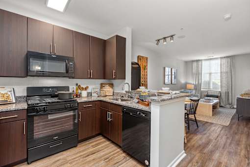 A kitchen with dark wood cabinets and black appliances.