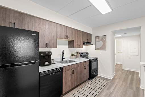 A kitchen with a black fridge, black dishwasher, and black oven.