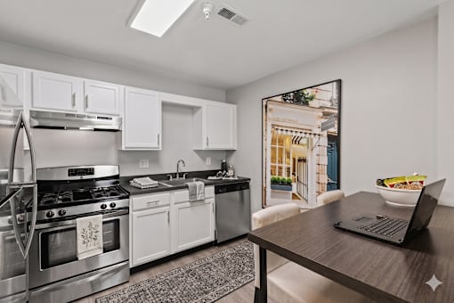 A modern kitchen with a stainless steel stove and white cabinets.