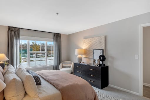 a bedroom with a bed and a dresser and a window at The Austin Apartment Homes, New Jersey