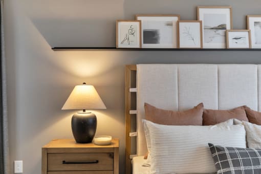 a bedroom with a bed and a nightstand with a lamp and pictures on the at The Austin Apartment Homes, Deptford, NJ, 08096