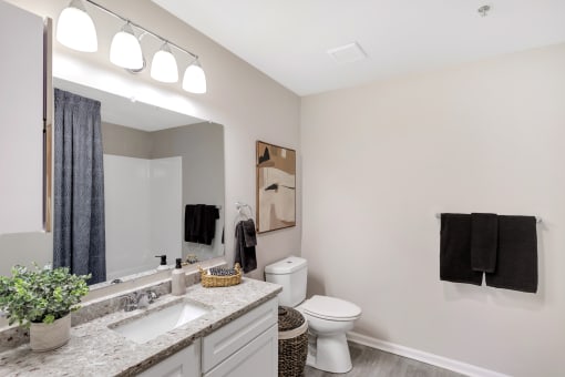 a bathroom with a toilet and a sink and a mirror at The Austin Apartment Homes, New Jersey, 08096