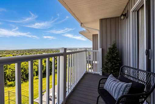 A balcony with a chair and a tree.