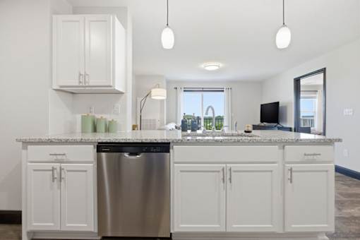 A modern kitchen with white cabinets and a granite countertop.