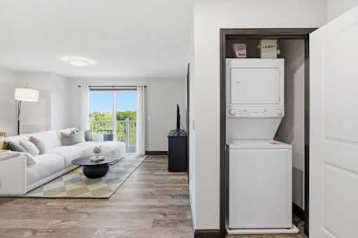 A white couch sits in a living room with a television and a washing machine in the background.