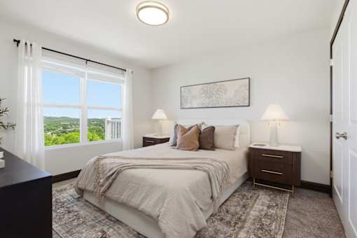 A bedroom with a large bed and a view of the city.