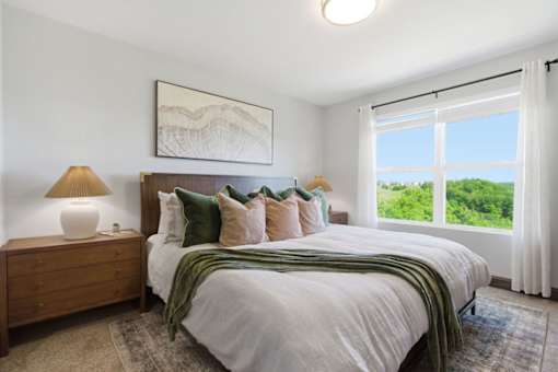 A bedroom with a large bed, a lamp, and a painting on the wall.