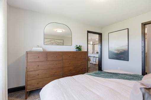 A bedroom with a large bed and a wooden dresser.