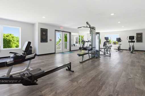 A gym with a variety of equipment including treadmills, weights, and exercise machines.