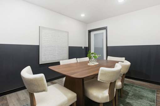 A dining table with four chairs and a vase with a plant on it.