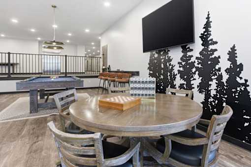 A modern dining room with a pool table and a television mounted on the wall.