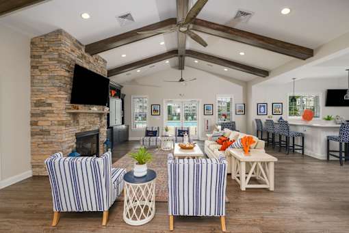A living room with a stone fireplace and striped chairs.