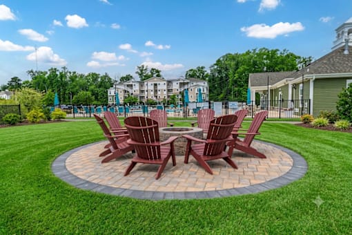 A set of four brown chairs are arranged around a circular table in a grassy area.