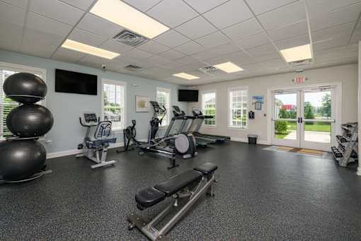 A gym with a variety of equipment including a treadmill, exercise bike, and weights.