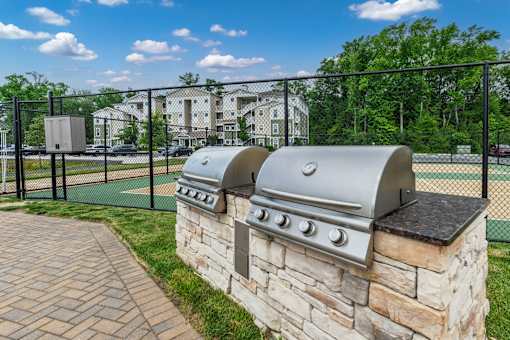 A stone wall with a built-in grill is in front of a fence.