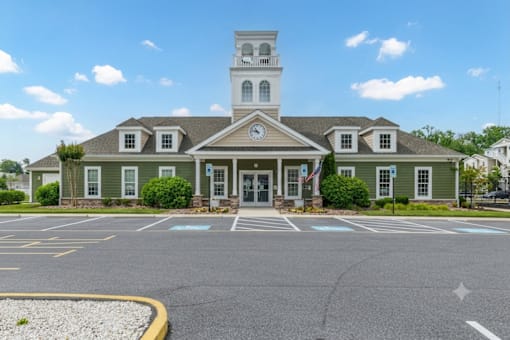 A church with a steeple and a clock tower is surrounded by a parking lot.