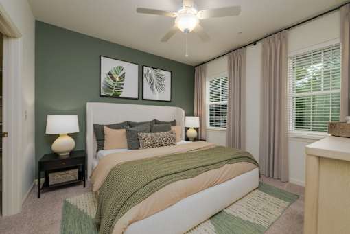 A bedroom with a bed, nightstand, and a ceiling fan.