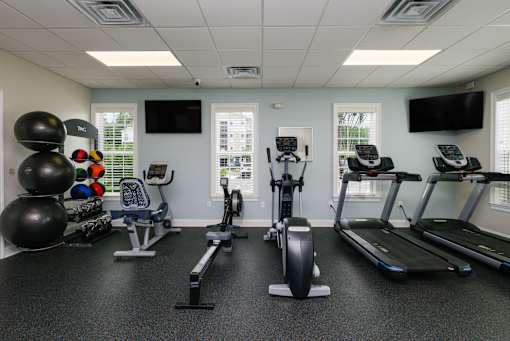 A gym with treadmills, elliptical machines, and exercise balls.