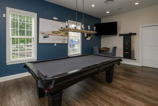 A pool table in a room with blue walls and wood flooring.