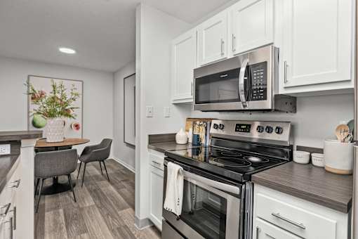 A modern kitchen with a stove top oven and microwave above it. at Eagle Ridge Apartments, Monroeville, PA