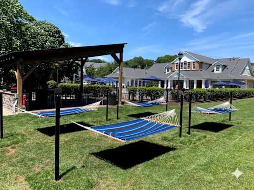 A blue hammock is strung between two poles in a grassy area.