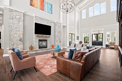 A living room with a stone fireplace and a brown leather couch.