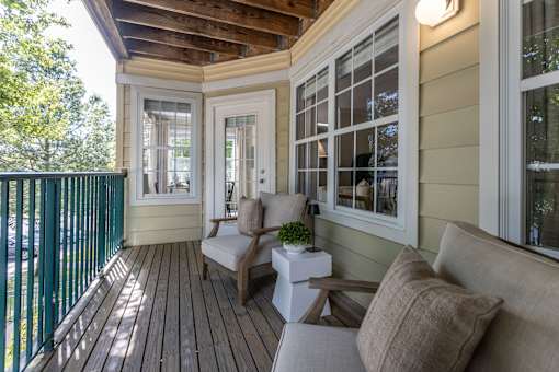 A small balcony with a couch, chair and table.