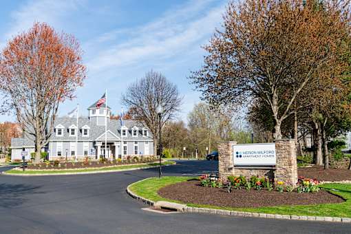A large building with a flag on top and a sign that says "Merion Millford Apartment Homes".