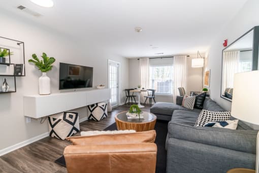 a living room with a gray couch and a tv at Merion Milford Apartment Homes, Milford