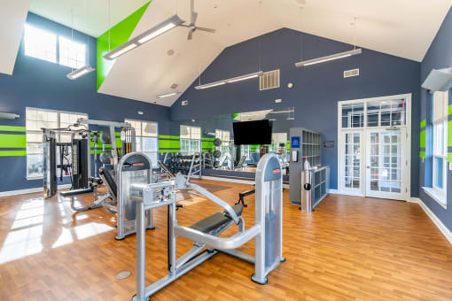 a gym with cardio equipment and weights in a building with windows at Merion Stratford Apartment Homes, Stratford, CT, 06614