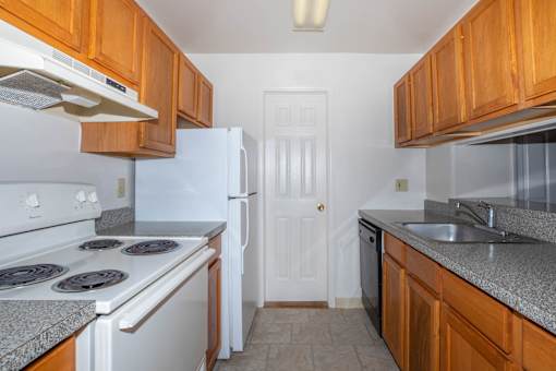 A kitchen with white appliances and wooden cabinets.
