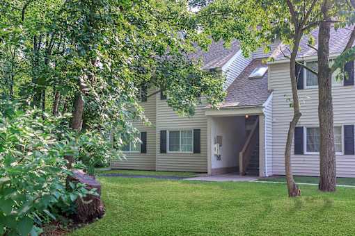 A house with a green lawn and trees in front.
