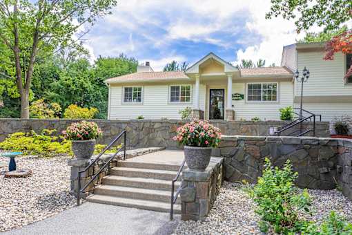 A house with a stone wall and steps leading to the front door.