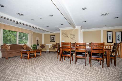 A living room with a brown couch, a coffee table, and a dining table with chairs.