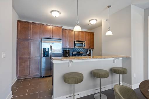 A kitchen with a bar stool and a fridge.