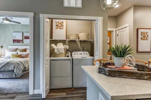 A laundry room with a washer and dryer is open to a bedroom.