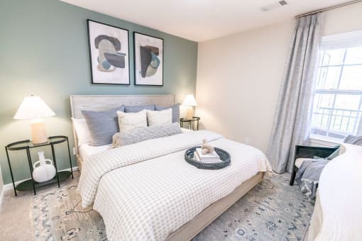 a bedroom with a bed and two windows at The Ledges Apartment Homes, Groton, CT, 06340