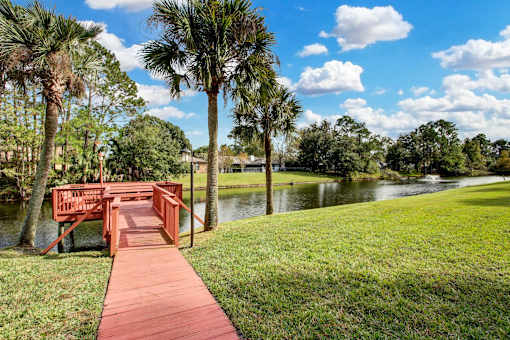 A wooden bridge over a body of water with palm trees in the background.