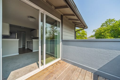 a balcony with glass sliding doors and a kitchen in the background
