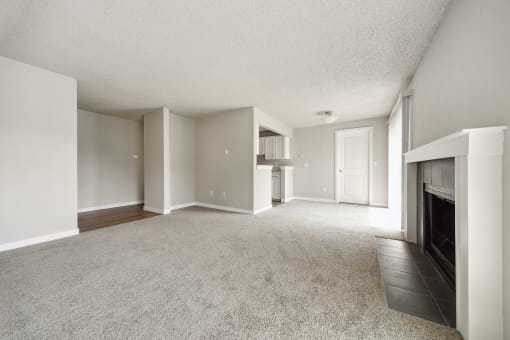a living room with a fireplace and a kitchen in the background