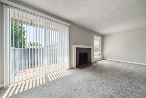 an empty living room with a fireplace and large windows