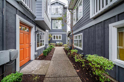 a walkway between two buildings with an orange door