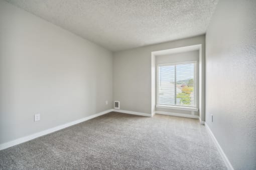 a bedroom with a large window and a carpeted floor