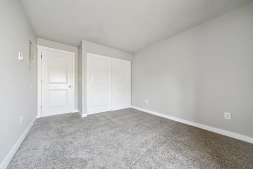 a bedroom with two doors and a carpeted floor