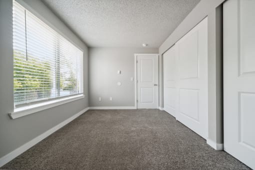 a bedroom with a large window and a carpeted floor