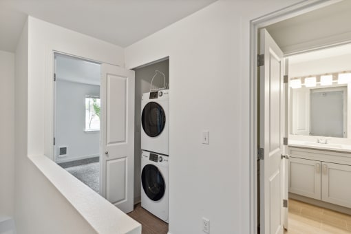 a washer and dryer in a living room with a door to a kitchen