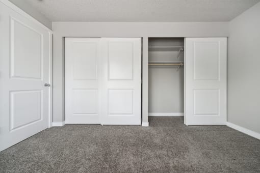 an empty bedroom with two doors and a closet
