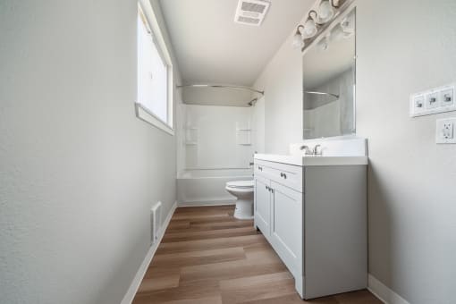a bathroom with a toilet sink mirror and shower in a 555 waverly unit